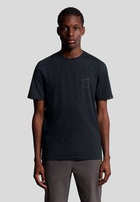 Zwart T-shirt met korte mouwen, gemaakt van katoen, met een klein logopatch op de linkerkant van de borst. Eenvoudige ronde halslijn, ontspannen pasvorm.