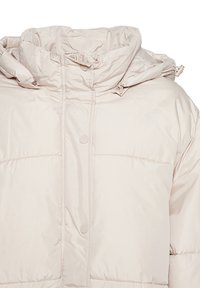 Pufová bunda svetlej béžovej farby, s vysokým golierom, gombíkovým zapínaním a prešívanou textúrou so viditeľnými stehmi.