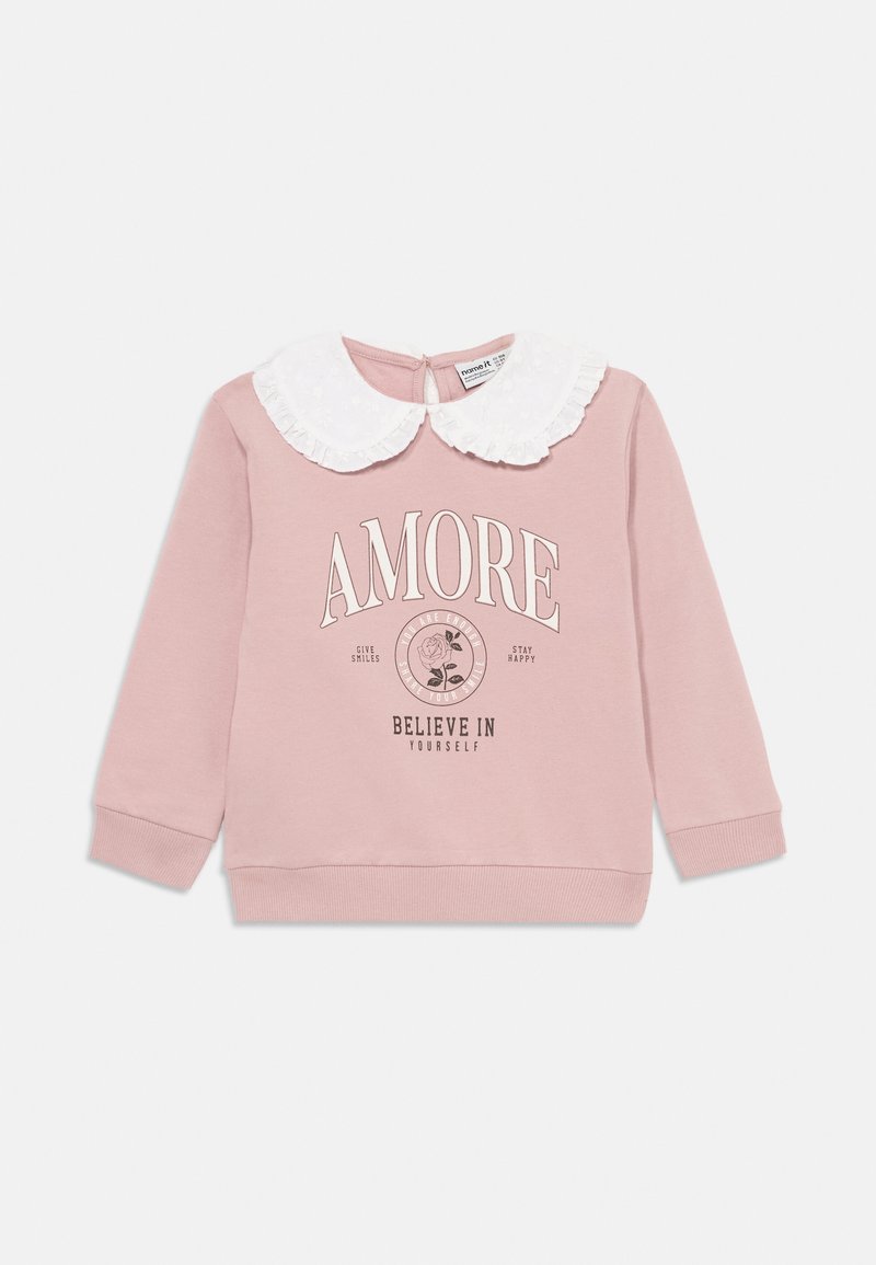 Sudadera rosa de mangas largas, con cuello de encaje blanco y texto impreso que dice "AMORE" con detalles florales. Tejido suave con puños acanalados.