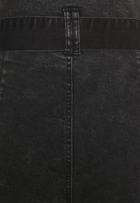 Jupe en denim noire avec une texture lisse, une large ceinture élastique et une couture centrale.