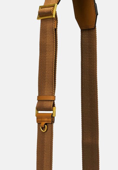 Sangle d'épaule en tissu marron avec quincaillerie dorée, dotée d'une accent en cuir et d'une boucle réglable. Texture lisse avec des coutures régulières.