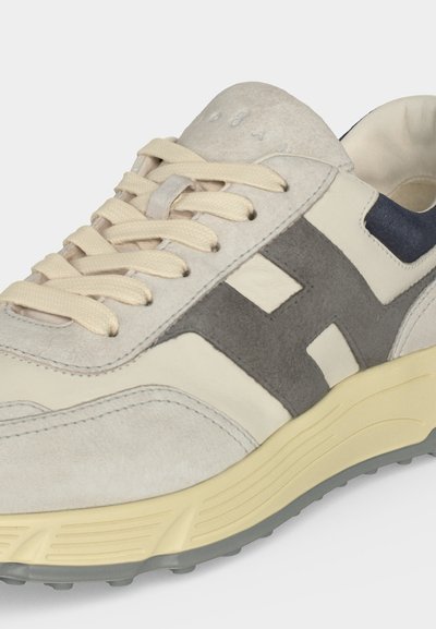 Baskets en daim beige et gris avec des lacets beiges, des bandes latérales grises et une semelle crème avec une bande de roulement grise.