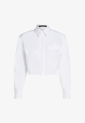 Bílá zkrácená košile na knoflíky s dlouhými rukávy, špičatým límcem a malým detailním kapsičkem na levé straně hrudi.