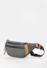 Sac banane gris en matériau synthétique, avec des fermetures éclair noires, des accents beiges et une sangle réglable avec une fermeture à boucle.