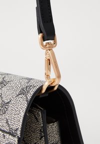 Primo piano di una borsa con motivo bianco e nero, con una tracolla nera attaccata da un gancio dorato inciso con "JOOP!".