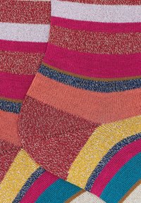 Calze colorate a righe lavorate a maglia con bande metalliche dorate, rosa, rosse, arancioni, blu, gialle e bianche, che mostrano talloni e punte sovrapposti.