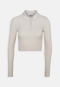 Przycięta koszulka polo z długim rękawem w jasnobeżowym prążkowanym materiale. Posiada klasyczny kołnierzyk i design z trzema guzikami.