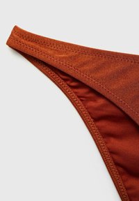 Costum de baie inferior în nuanță de portocalie ruginită, realizat dintr-un material cu textură netedă, având o talie subțire și cusături plate pentru un design minimalist.