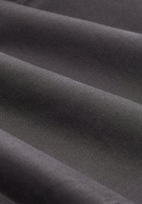 Tejido gris oscuro con una superficie suave y ligeramente texturizada, que presenta sutiles nervaduras diagonales y pliegues en el material.