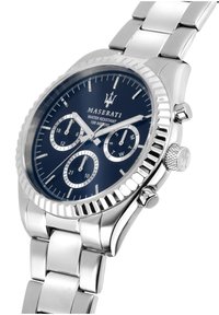 Silverfärgad rostfri klocka med en marinblå urtavla, som har tre underdials, en texturerad bezel och ett polerat armband. Vattentålig.