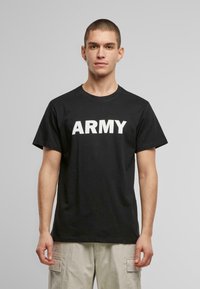 Juodas medvilnės marškinėlis su dideliu baltu užrašu "ARMY" per krūtinę. Klasikinis apvalus kaklas ir trumpi rankoviai, laisvas kirpimas.