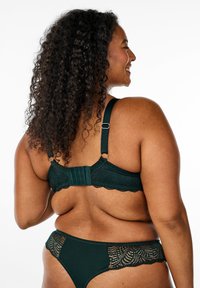 Dark green lace bra and matching underwear with scalloped edges and adjustable straps. Bra features a hook-and-eye closure at the back.