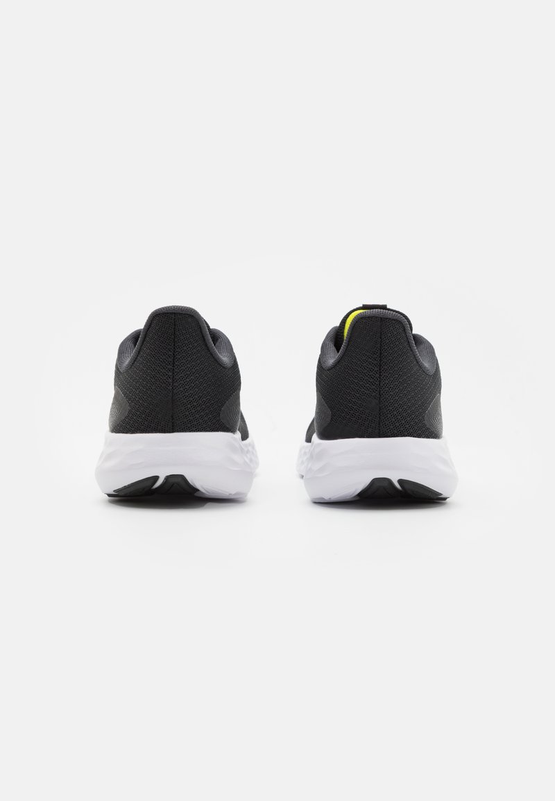 Scarpe da corsa nere con tomaia in mesh testurizzato e suola bianca. La vista posteriore mostra un accento giallo sul tallone e un design leggero.