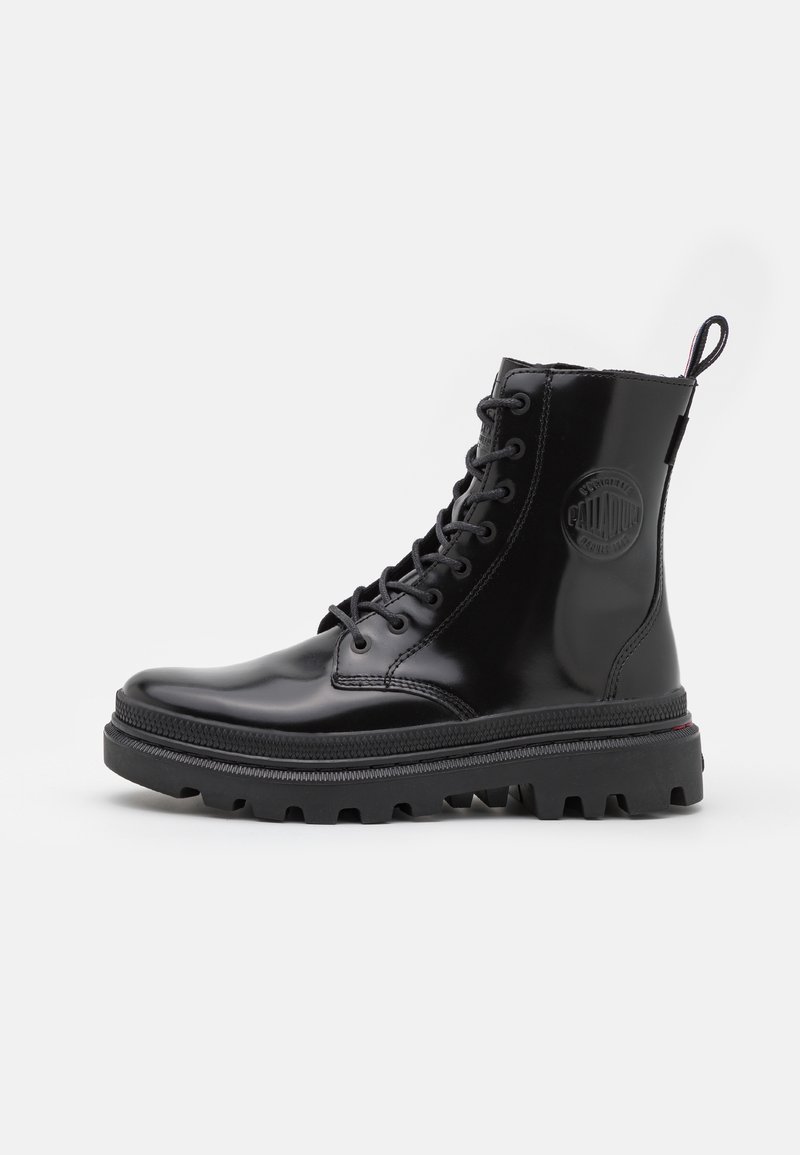 Botte de combat noire en cuir brillant à lacets avec une semelle épaisse à crampons et un passant à l’arrière, présentée de profil sur fond blanc.