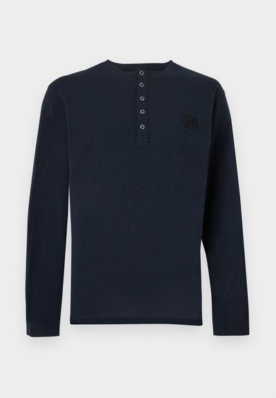 Μπλούζα henley με μακριά μανίκια σε ναυτικό μπλε χρώμα, βαμβακερό ύφασμα, πέντε κουμπιά στο μπροστινό μέρος, στρογγυλή λαιμόκοψη, κυκλικό λογότυπο στο αριστερό στήθος, μινιμαλιστικός σχεδιασμός.