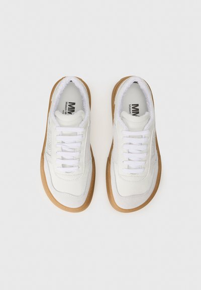 Vita sneakers med en blandning av släta och mocka-texturer, med en gummisula och vita snören, visade från ovan.
