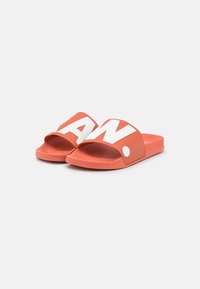 Orange slide sandals with a wide, molded strap featuring bold white lettering. Smooth texture, flat sole, and circular accent detail.