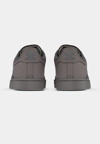 Γκρι σουέντ αθλητικά παπούτσια με χαμηλή σχεδίαση, διαθέτουν υφή στη φτέρνα, ανάγλυφο λογότυπο στο πίσω μέρος και καουτσούκ σόλα. Μινιμαλιστικό στυλ.