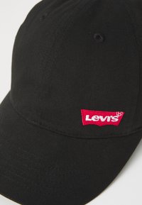 Căciulă de baseball neagră, din twill de bumbac, având un logo roșu brodat Levi's pe față, cu o margine curbată și un material texturat.