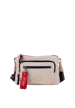 Bolso beige de hombro hecho de material sintético, con cremallera azul marino, un bolsillo frontal y una etiqueta de marca roja. Correa ajustable con detalles en azul marino y rojo.