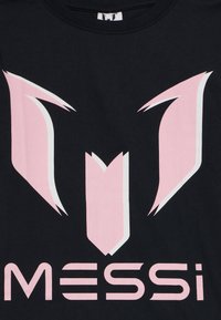Melnā T-krekls ar lielu rozā un baltu logo dizainu, kas satur leņķiskas formas un vārdu "MESSI" resnā tekstā apakšā.