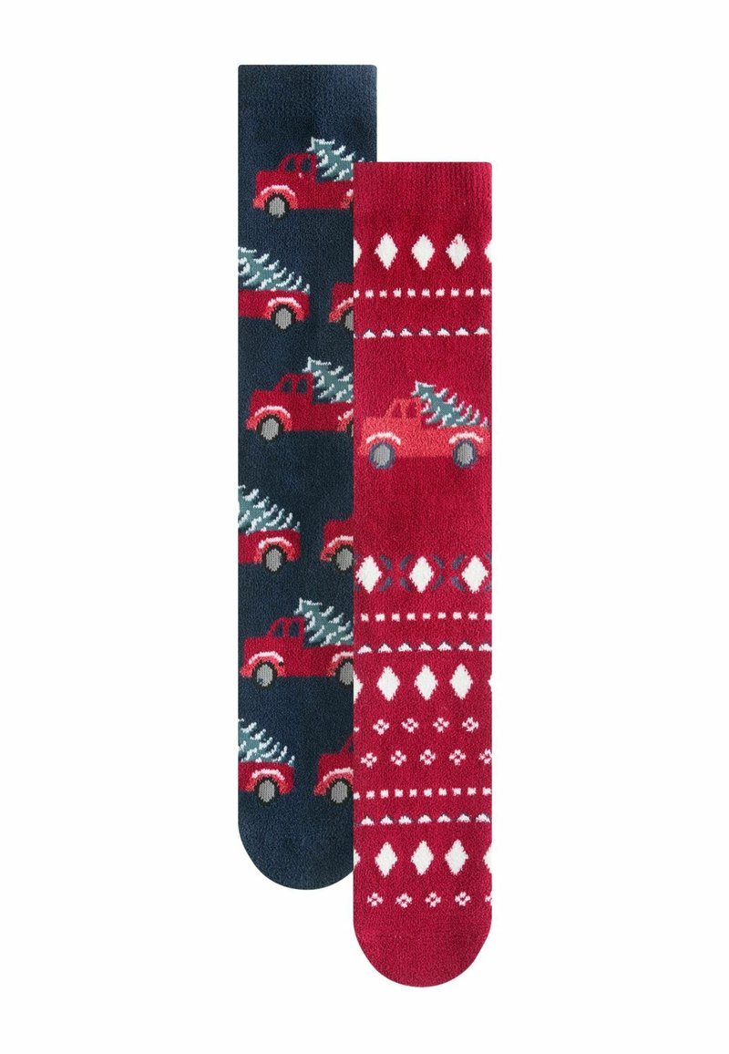 Dos pares de calcetines: uno azul marino con camiones rojos que llevan árboles de Navidad, el otro rojo con patrones de diamantes y árboles en blanco. Textura de punto.