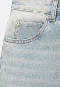 Poche de jean en denim délavé bleu clair avec rivets métalliques, coutures contrastantes orange et détail de passant de ceinture.