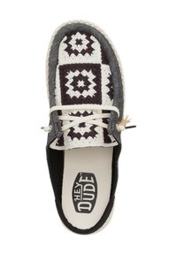 Zapatilla de lona sin cordones en blanco y negro con un patrón, puntera redonda, cordones blancos y un logo en el interior de la plantilla beige.