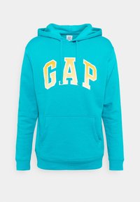 Sudadera con capucha de color turquesa con un bolsillo frontal tipo canguro, que presenta el logo "GAP" en blanco y amarillo en el pecho. Textura de tela suave.