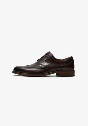 Muške tamnocrne kožne elegantne cipele s brogue detaljima, vezicama i niskom drvenom štiklom na bijeloj pozadini.