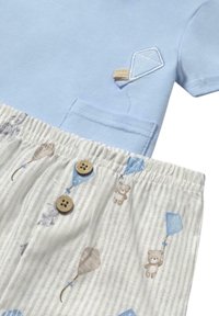 Camiseta de algodón azul claro con bordado de cometa, combinada con pantalones cortos a rayas crema con patrones de animales y cometas, y botones de madera marrón.