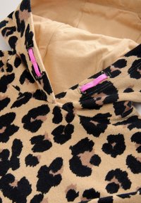 Leopard-print hoodie with beige body, black and brown spots, featuring a soft texture and pink hardware accents on the neckline.