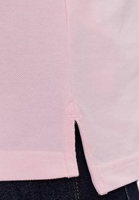 Camiseta de algodón de color rosa claro con un tejido texturizado, aberturas laterales y costuras en contraste a lo largo del dobladillo y las costuras.