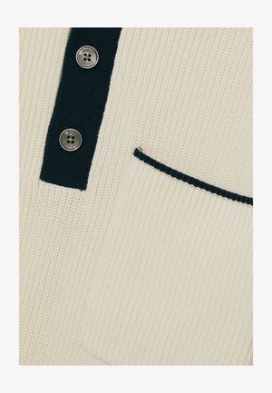 Krém színű bordás pulóver, amely sötétkék gallérral, két fémbotrány gombbal és sötétkék díszítésű zsebbe varrott zsebbel rendelkezik. Puha, textúrált anyag.