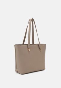 Béžová taška přes rameno s hladkou texturou, dvěma úzkými uchy a zlatými kovovými detaily na stranách. Obdélníkový tvar a otevřený vrchní design.