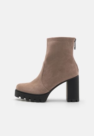 Wildleder-Ankle-Boots in Hellbraun mit einem kräftigen schwarzen Blockabsatz, ausgestattet mit einem seitlichen Reißverschluss und genähten Details entlang der Kanten.