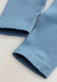 Tissu bleu côtelé avec une texture lisse, présentant des poignets repliés qui affichent une finition soignée et des détails de couture subtils.