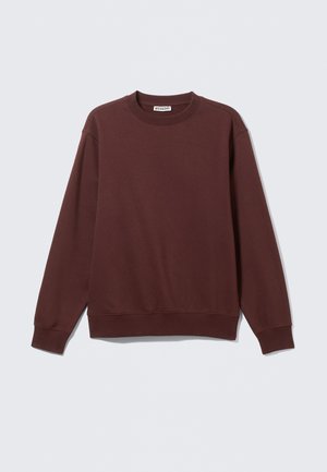 Mørkerød sweatshirt lavet af blødt stof, lange ærmer og rund halsudskæring. Har ribbede manchetter og kant. Brøndmærket er synligt indeni halsen.
