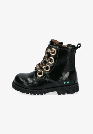 Botín de charol negro con ojales dorados, cordones de estampado de leopardo, acabado texturizado y acentos de puntos verdes en el costado.