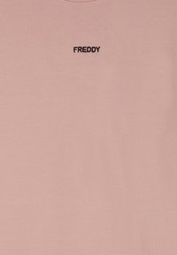 Camiseta de algodón rosa con cuello redondo y un pequeño logo "FREDDY" bordado en negro en el pecho. Textura suave y lisa.