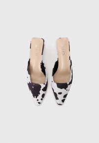 Escarpins slingback à imprimé vache avec un bout pointu, fabriqués en matériau pelucheux. Présente un design à découpe basse et une semelle intérieure de couleur neutre.