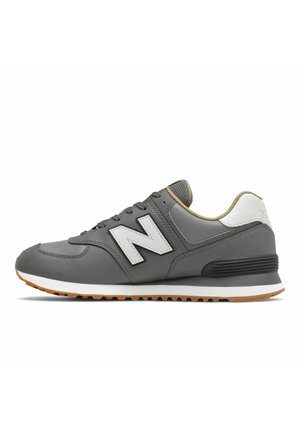 Grå og hvid New Balance sportssko med gummisål, mesh-sål, og side "N" logo, vist i profil på hvid baggrund.