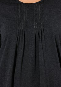 Schwarze Tunika mit Rundhalsausschnitt, vertikalen Falten und subtiler metallic Fadenverarbeitung sowie einem weichen, strukturierten Stoff.