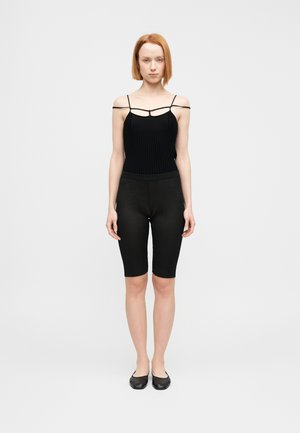 Czarny prążkowany body na cienkich ramiączkach w zestawieniu z czarnymi szortami do kolan. Strój ma dopasowaną sylwetkę i minimalistyczny design.