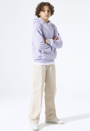 Sweat à capuche lavande, coupe décontractée avec une capuche, associé à un pantalon beige clair à jambes droites, complété par des baskets blanches. Design simple et moderne.