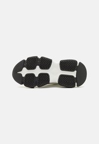Black sole with patterned rubber tread, white midsole, featuring segmented sections for flexibility and traction. Minimalist design.
