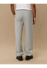 Grå sweatsbukser lavet af blød stof, med en afslappet pasform, elastisk talje, sidelommer og ribbede kanteder. Designet til komfort og nemhed.