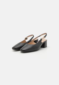 Sorte skinn slingback-sko med firkantet tå, lav blokkheel, og dekorativt hardware i gulltone på stroppen. Glatt tekstur.