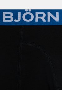 Sorte boxer-truser med en blå elastisk midje som har merkevarenavnet "BJÖRN" i hvitt. Glatt tekstur og tettsittende design.