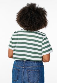 T-shirt à manches courtes rayé vert et blanc avec un col rond, associé à un jean en denim bleu taille haute.